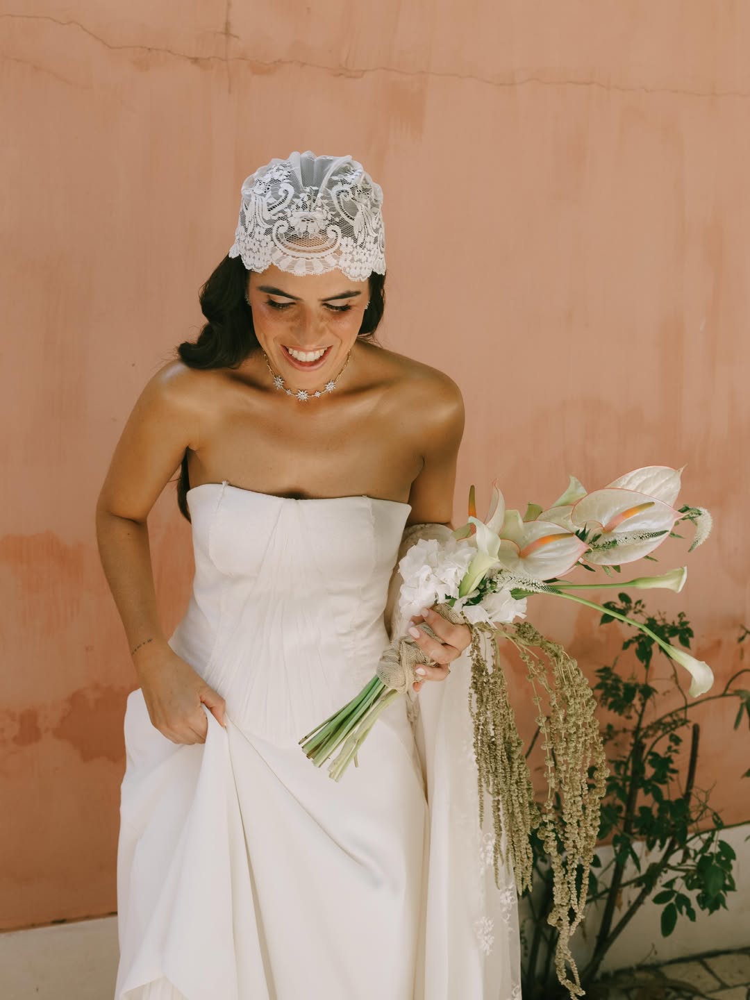 Smiling bride in a white gown holding a floral bouquet